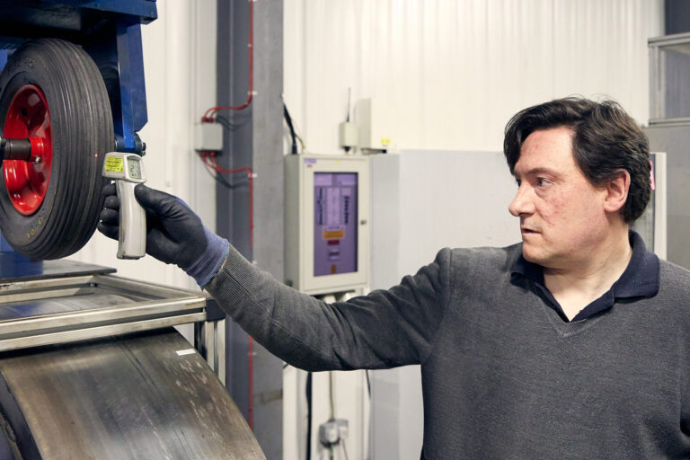 Person measuring heat build-up in a PU tire after a load test