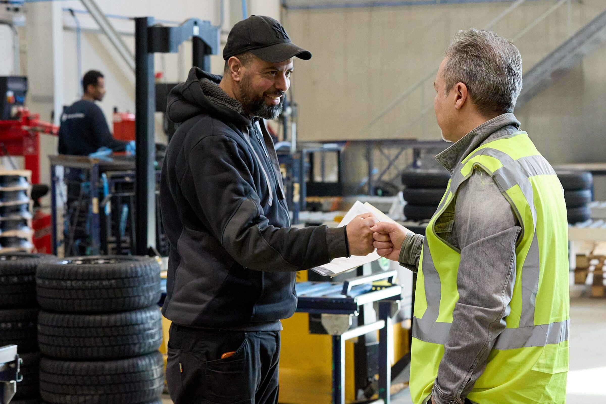 Two KENDA employees fist bumping in the warehouse of KENDA's new logistics centre in Turnhout, Belgium